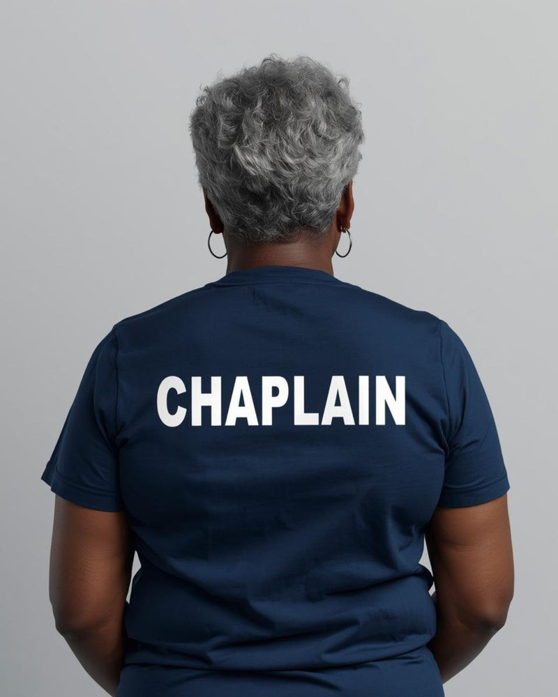 Person wearing a navy blue shirt with 'CHAPLAIN' printed on the back against a gray background
